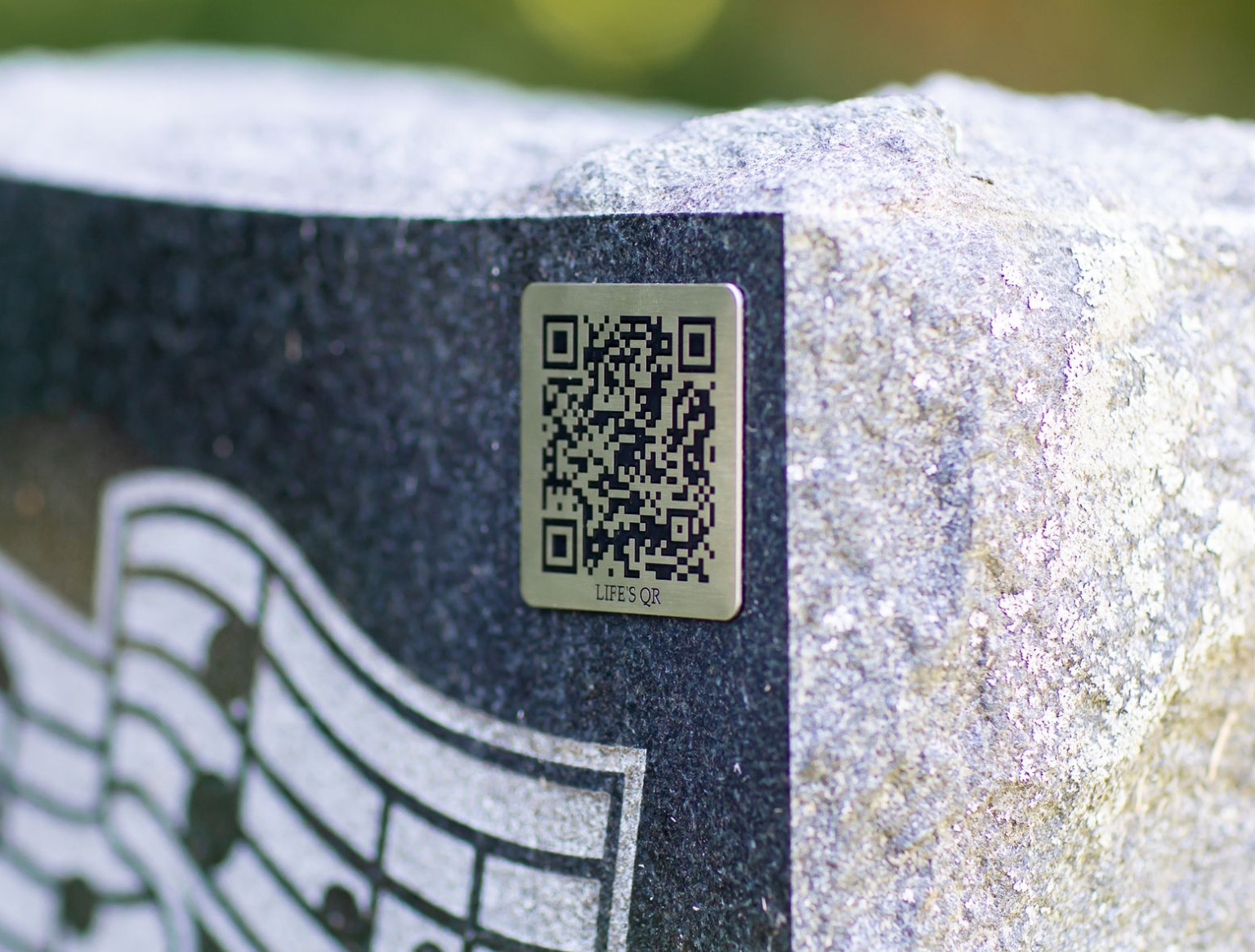 QR code plaque mounted on a granite headstone.