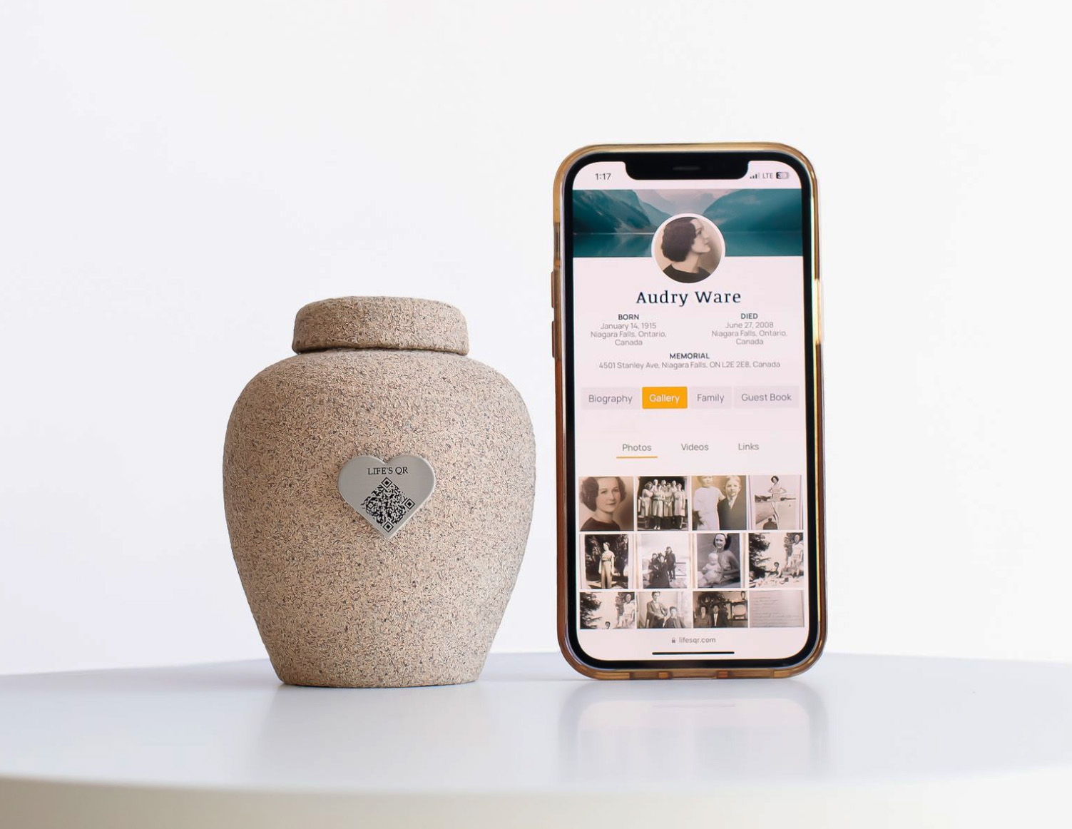 Memorial urn with a “Life’s QR” plaque beside a smartphone displaying a digital memorial profile.