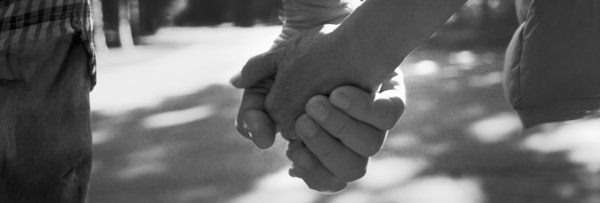 Close-up of two hands clasped together, conveying support and empathy.