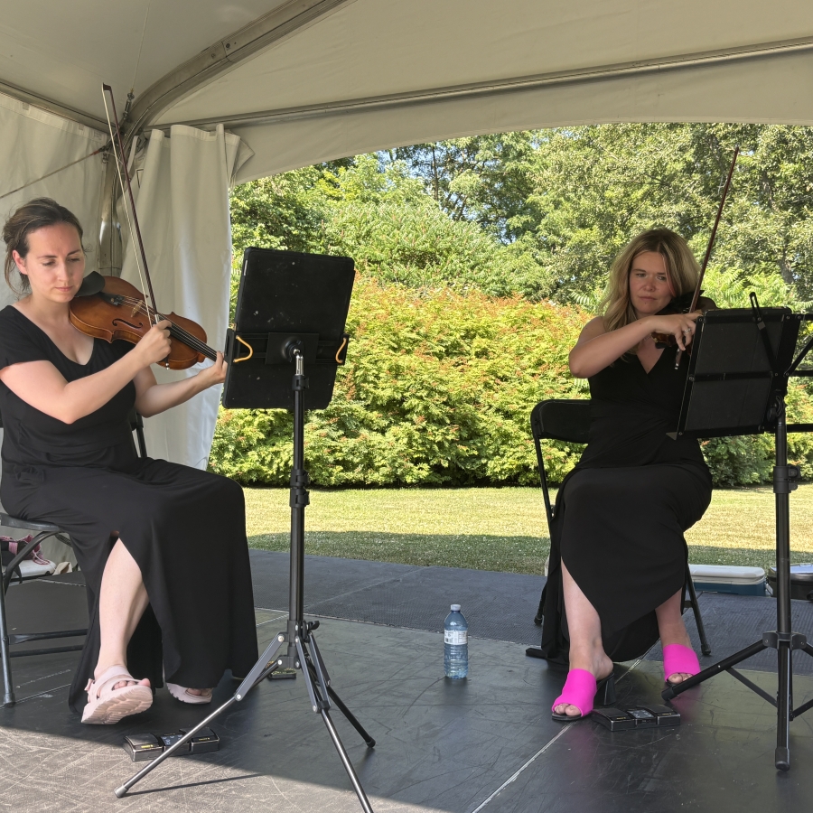 two women playing instruments under a tent