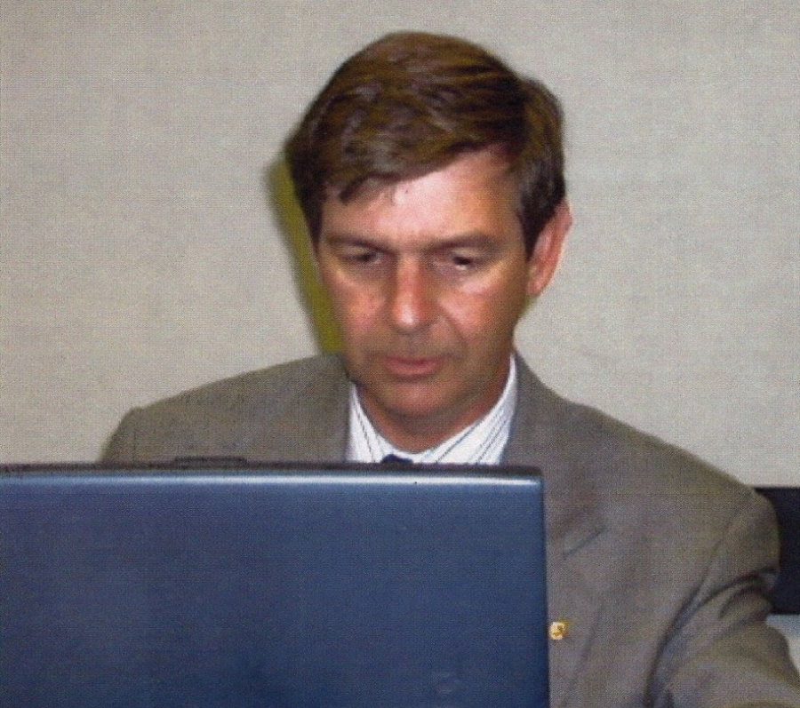 Person working on a laptop at a table with a drink can beside them.