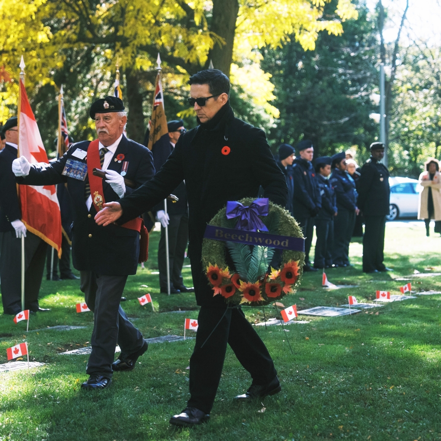 Wreath being carried during a remembrance ceremony at a cemetery.