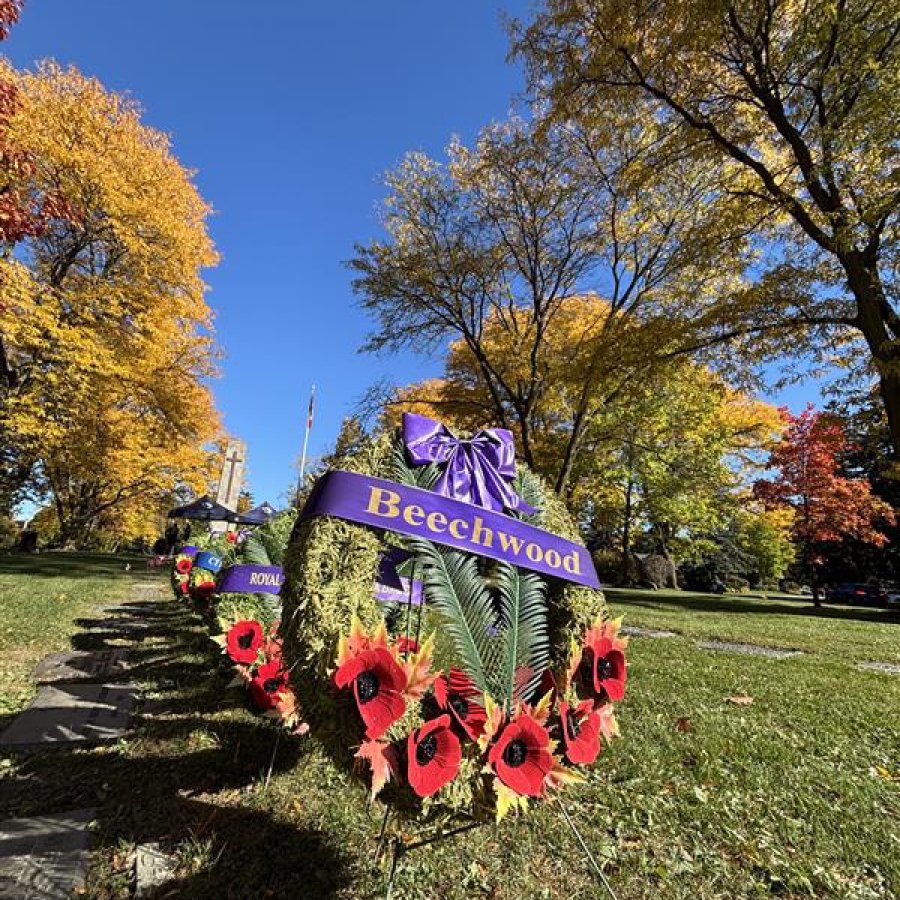 Poppy wreath at Beechwood Cemetery along a tree-lined path in autumn.