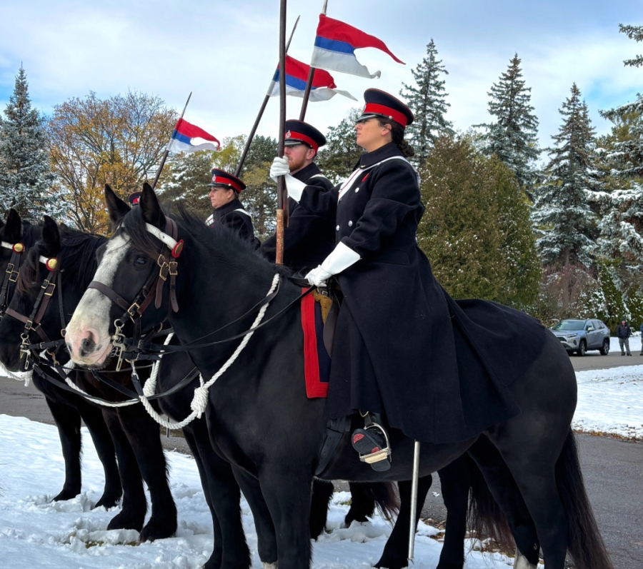 Mounted honor guard holding flags during Remembrance Day service at York Cemetery.