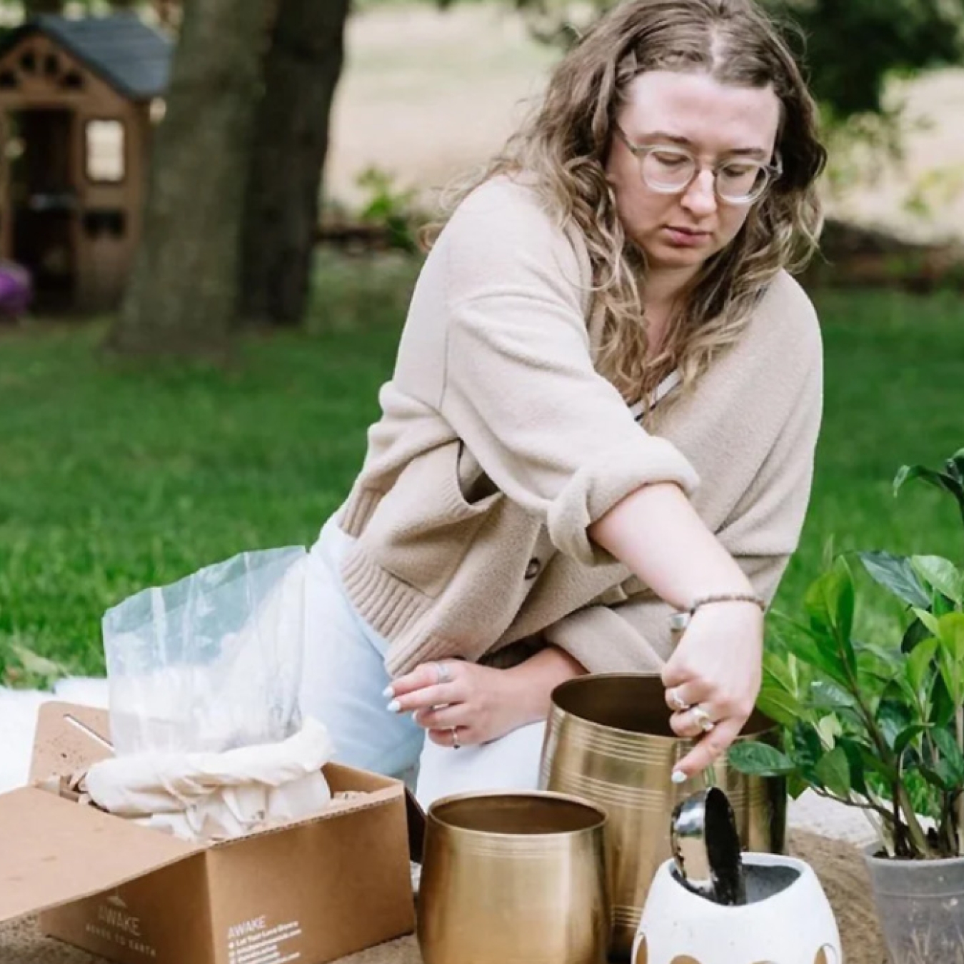 Person placing items into decorative urns while gardening outdoors.