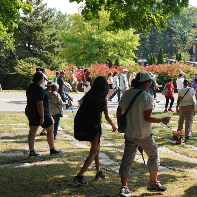 Group of visitors walking through Mount Pleasant Cemetery during a guided history tour.