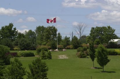 grass and tress with big Canadian flag