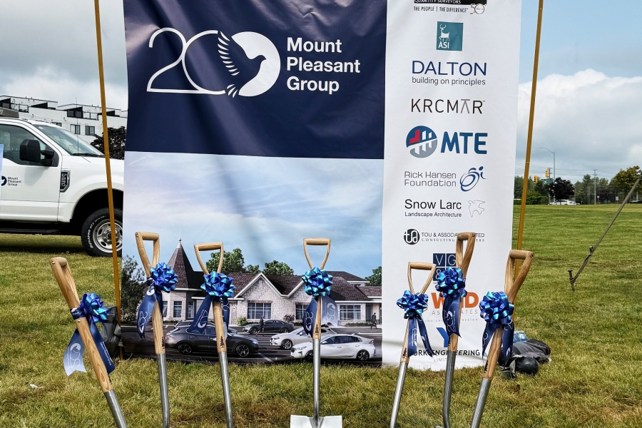 Generating response Copilot said: Ceremonial shovels with blue ribbons displayed in front of a Mount Pleasant Group groundbreaking event banner.