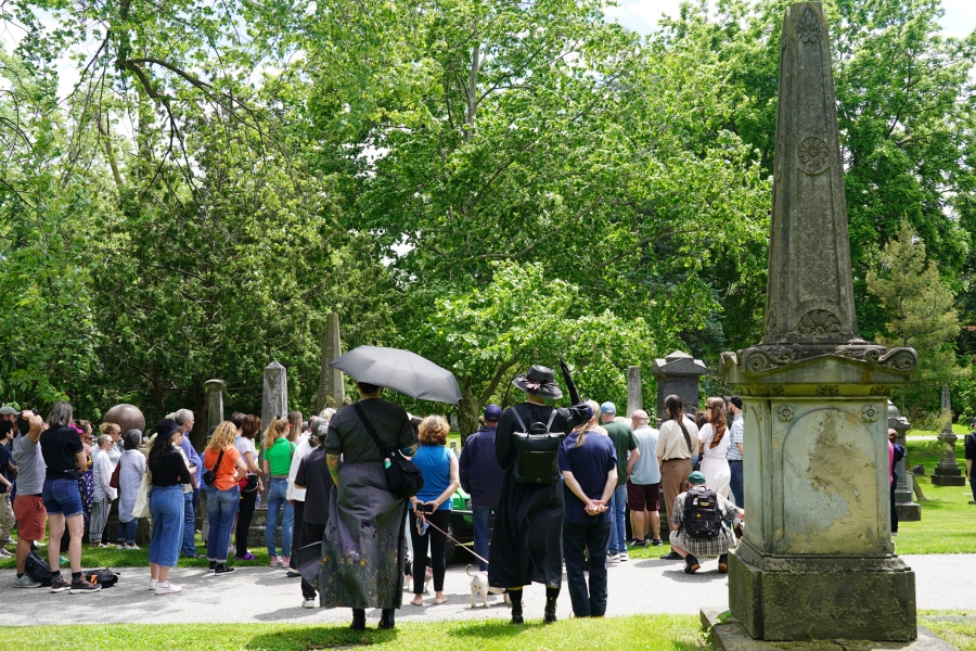 History walk with attendees gathered beside historic grave monuments.