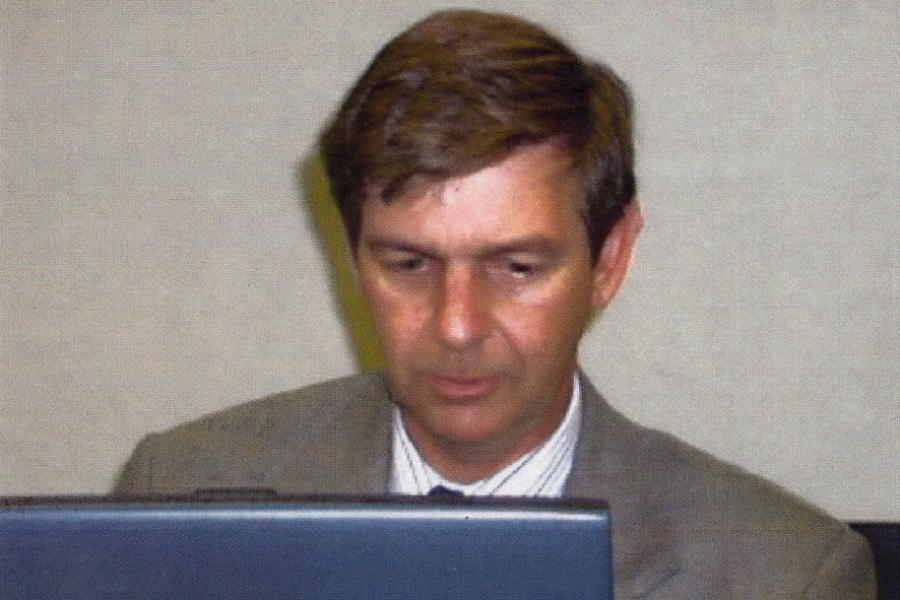 Person working on a laptop at a table with a drink can beside them.