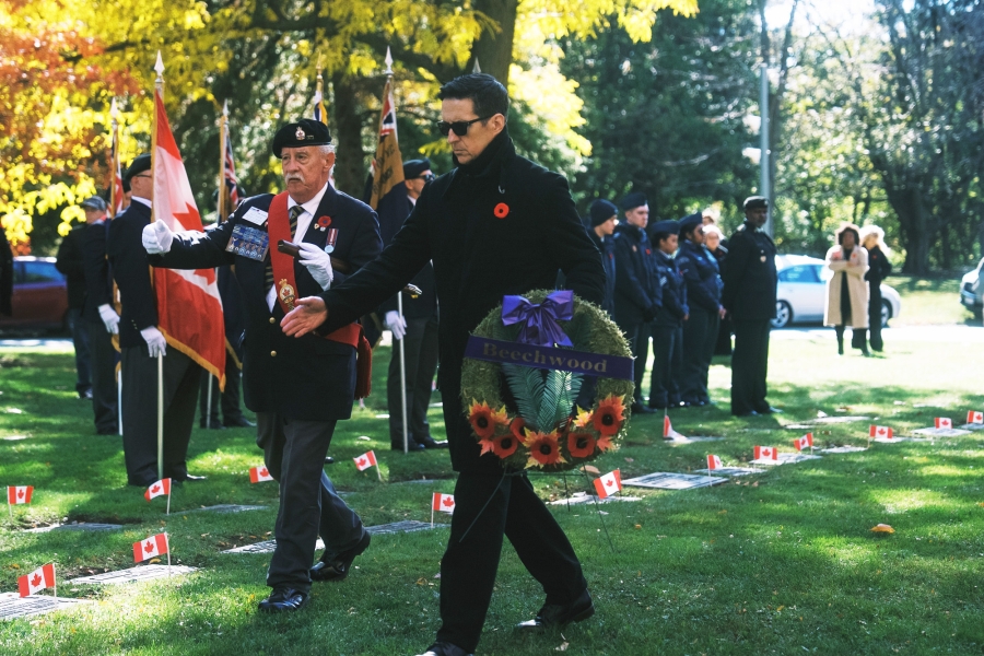 Wreath being carried during a remembrance ceremony at a cemetery.