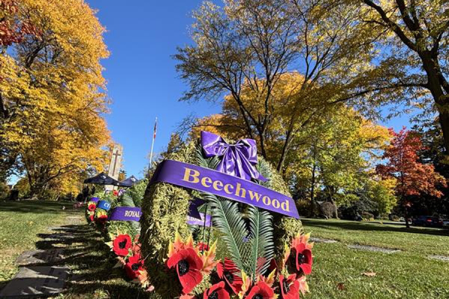 Poppy wreath at Beechwood Cemetery along a tree-lined path in autumn.