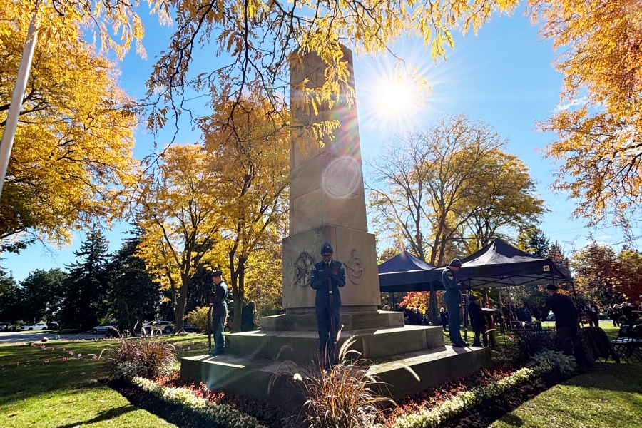 Stone memorial with wreaths under autumn trees and sunlight.