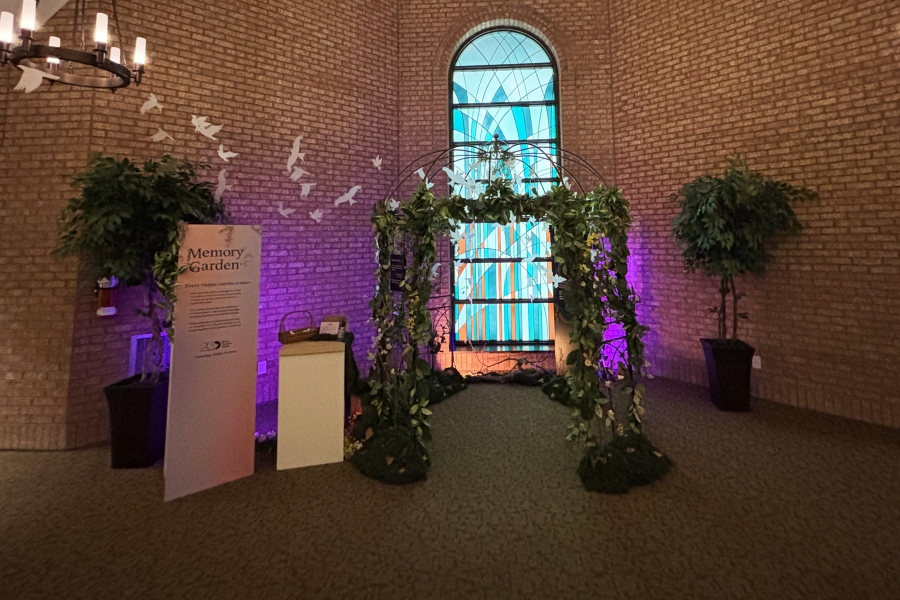 Memory garden display with leafy arch and stained-glass window backdrop.