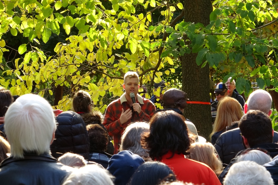 An arborist leading an educational session on urban forestry with people gathered around.
