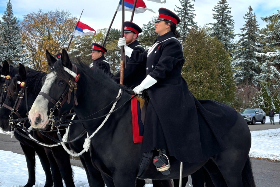 Mounted honor guard holding flags during Remembrance Day service at York Cemetery.