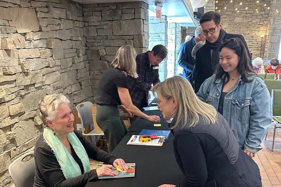 Book signing event with attendees gathered around a table.