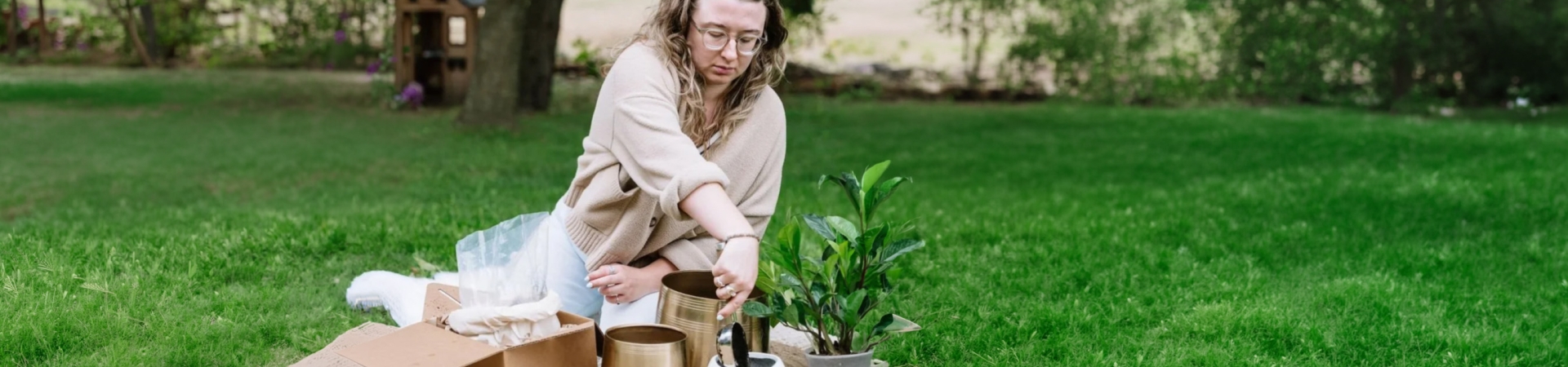 Person placing items into decorative urns on a grassy lawn.